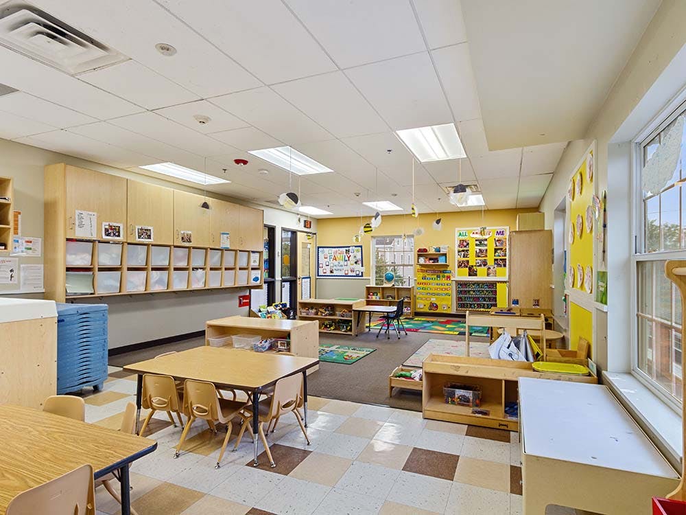 Classroom with small tables and chairs, storage cabinets, and windows