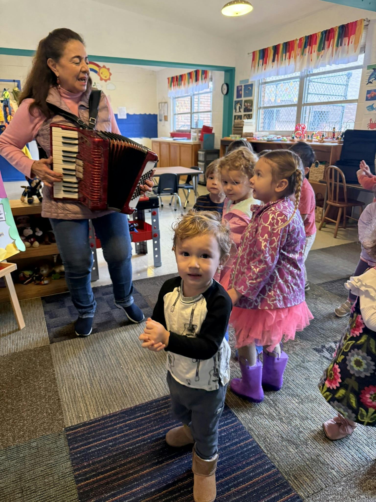 Person playing accordion for children in a classroom