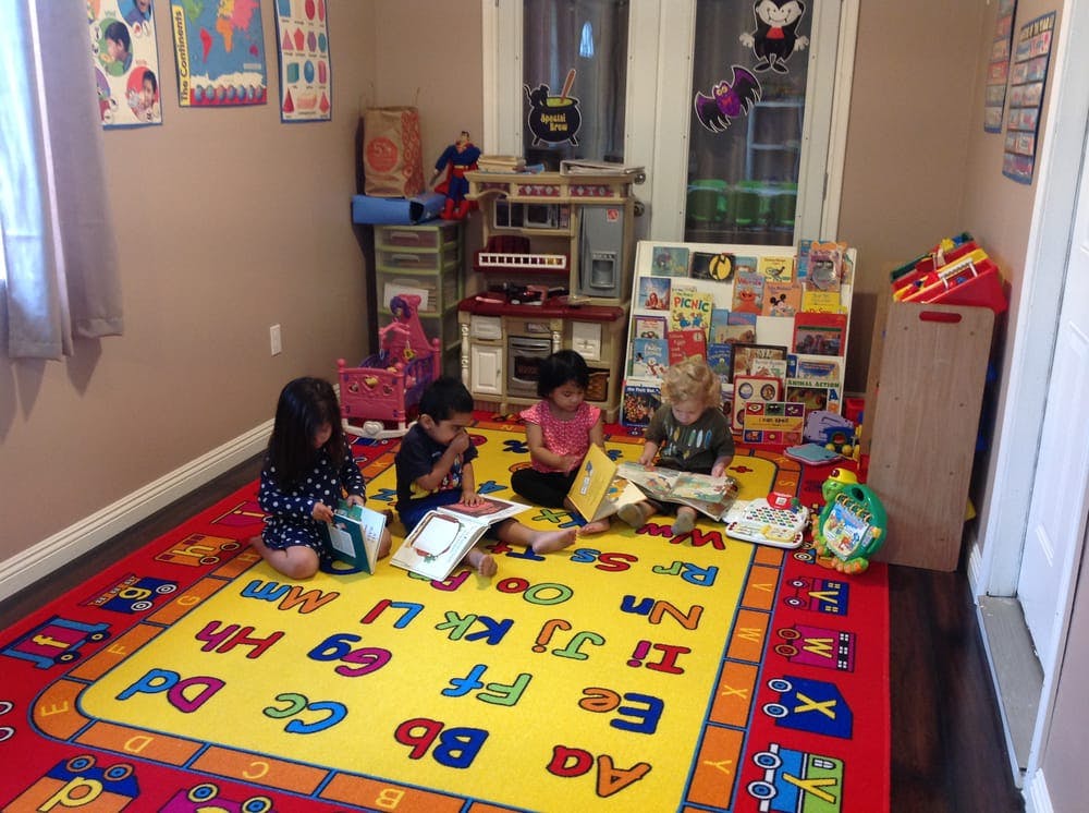 Children sitting on an alphabet rug reading books in a classroom