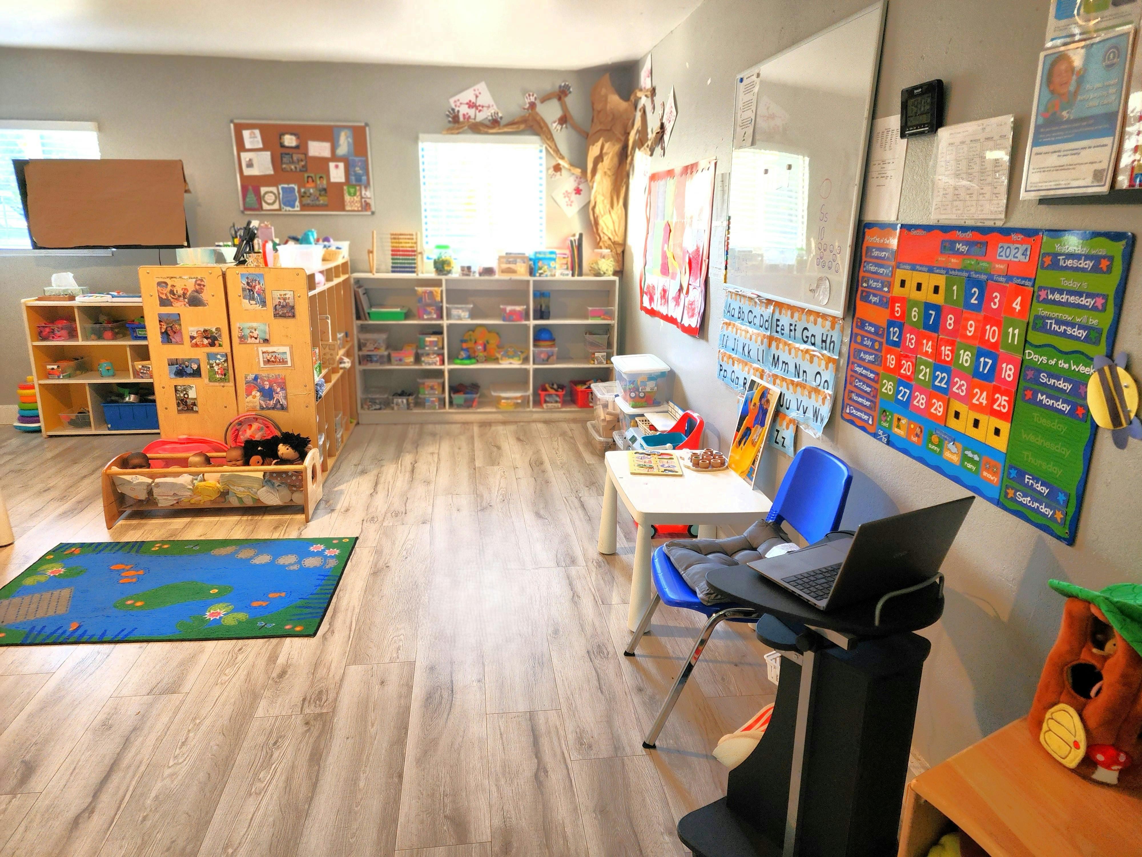 Classroom with shelves of toys, a rug, and a calendar on the wall