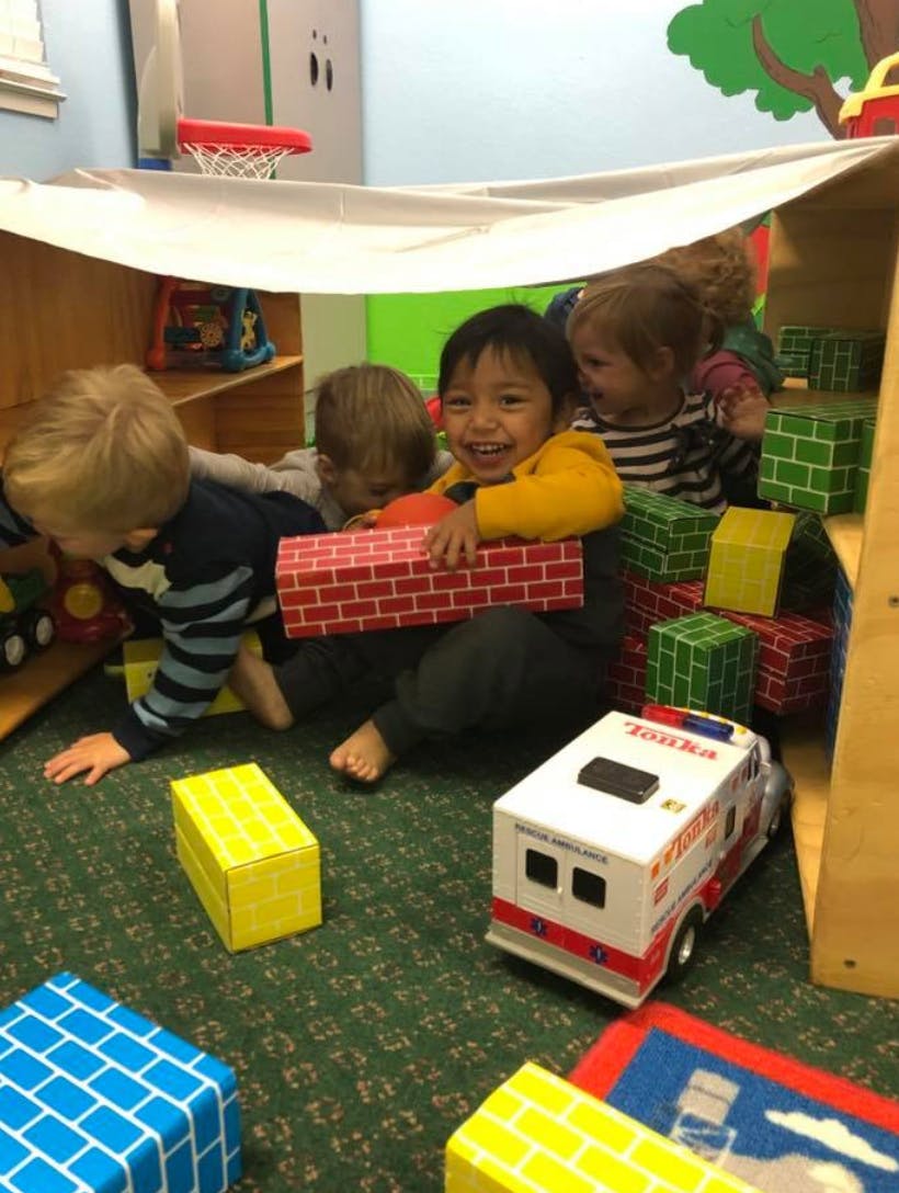 Children playing with toy blocks and a toy ambulance in a play area