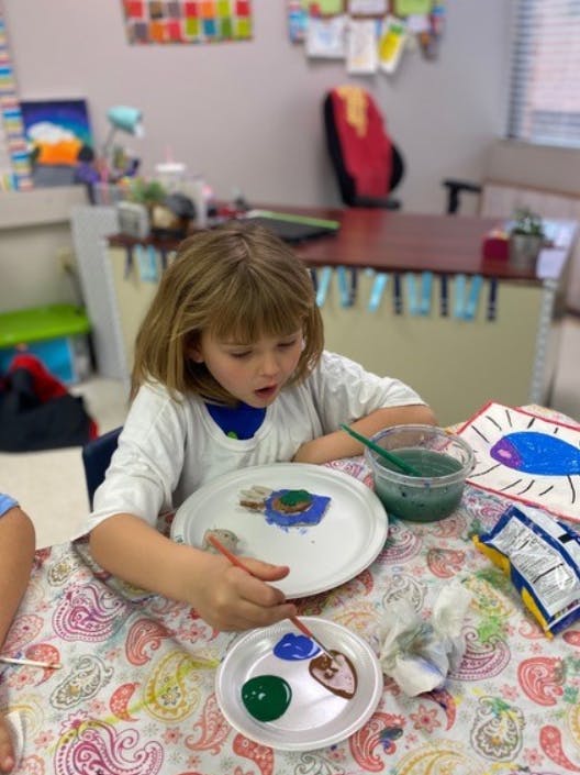 Child painting a craft in a classroom