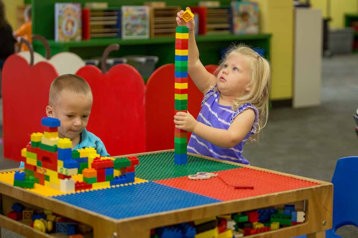 Two children playing with colorful building blocks at a table