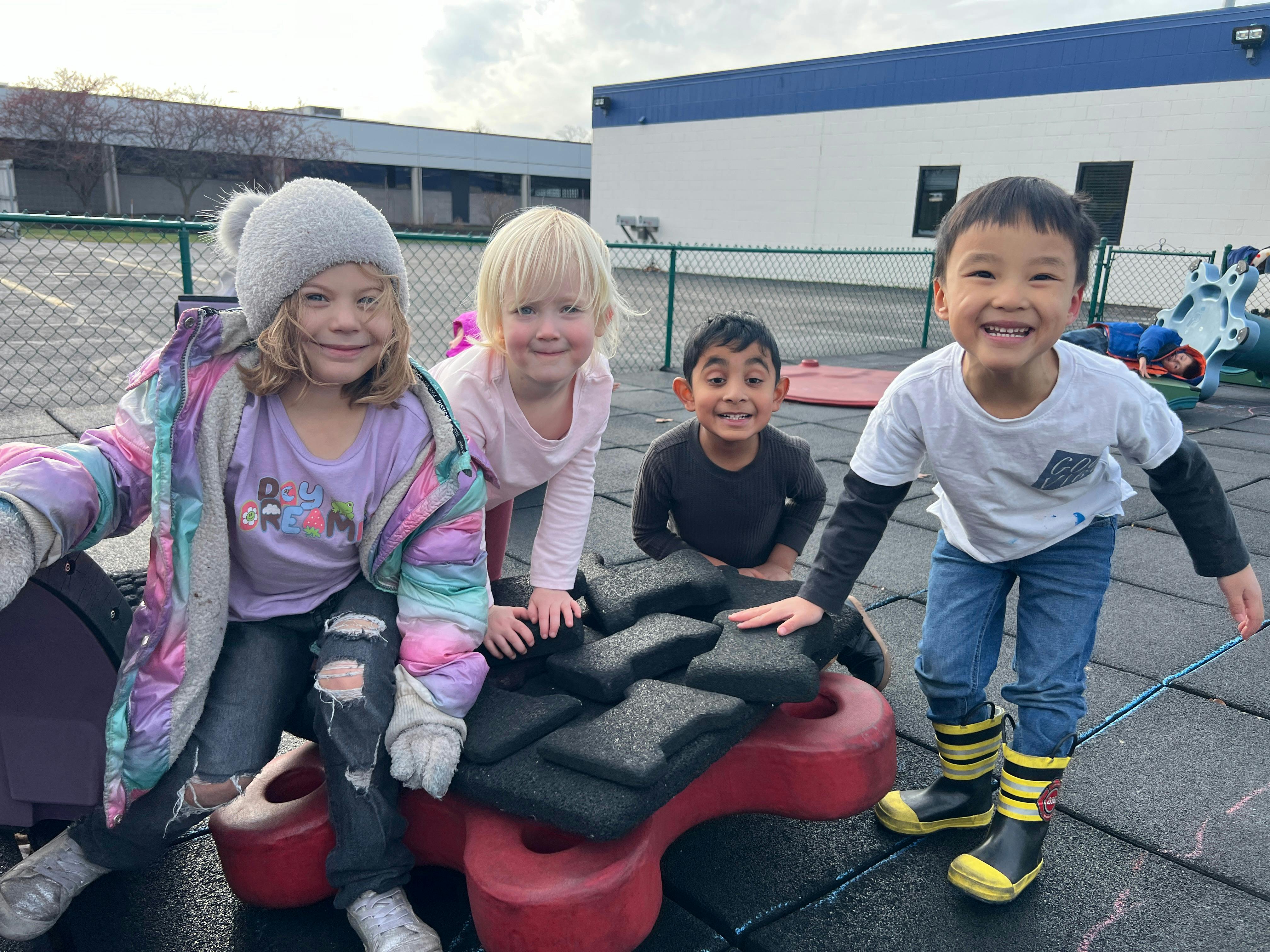 Four young children posing together on a playground