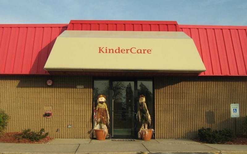 KinderCare sign above a building entrance with scarecrows