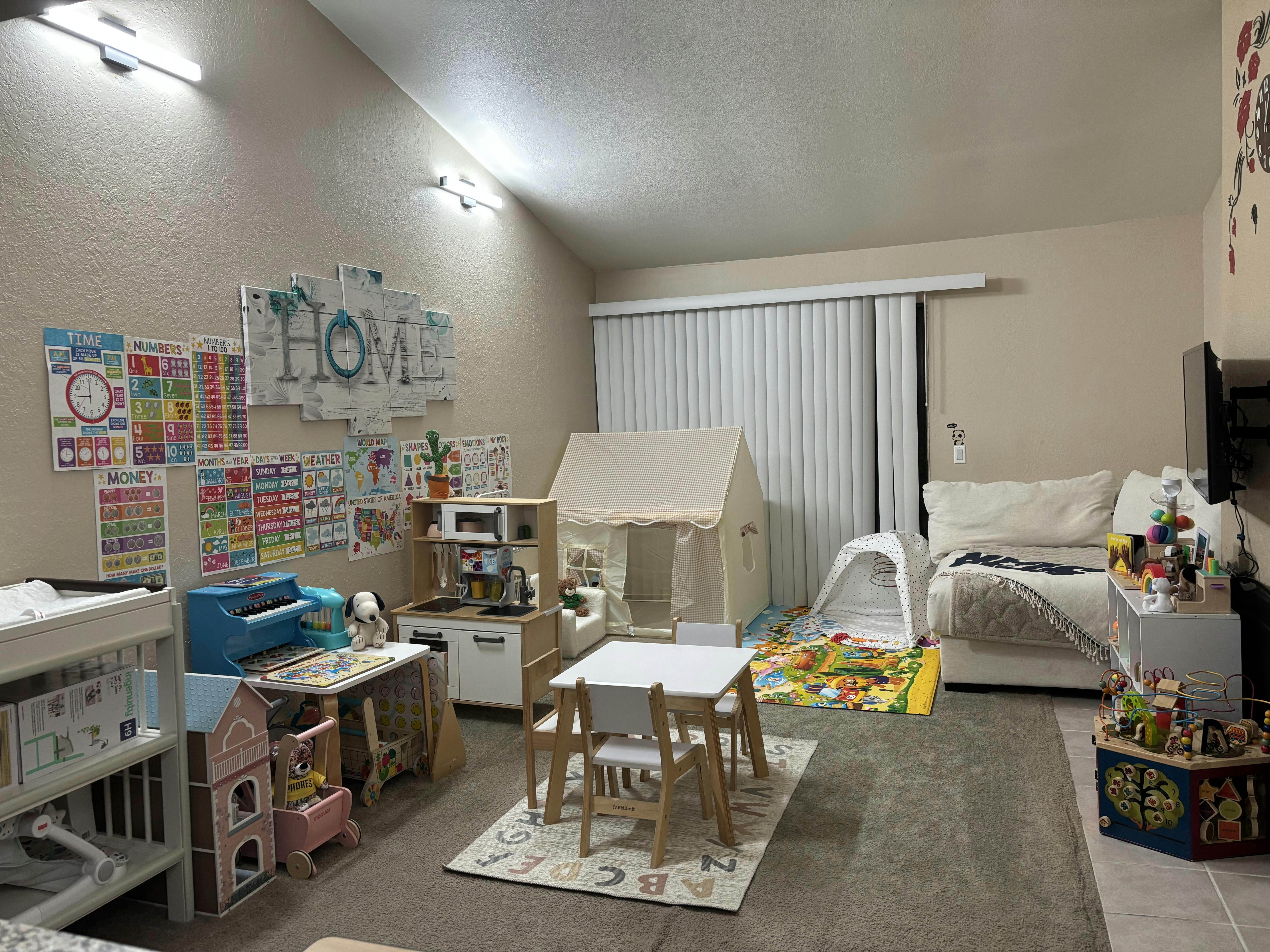 Children's play area with play kitchen, tent, and learning posters on the walls