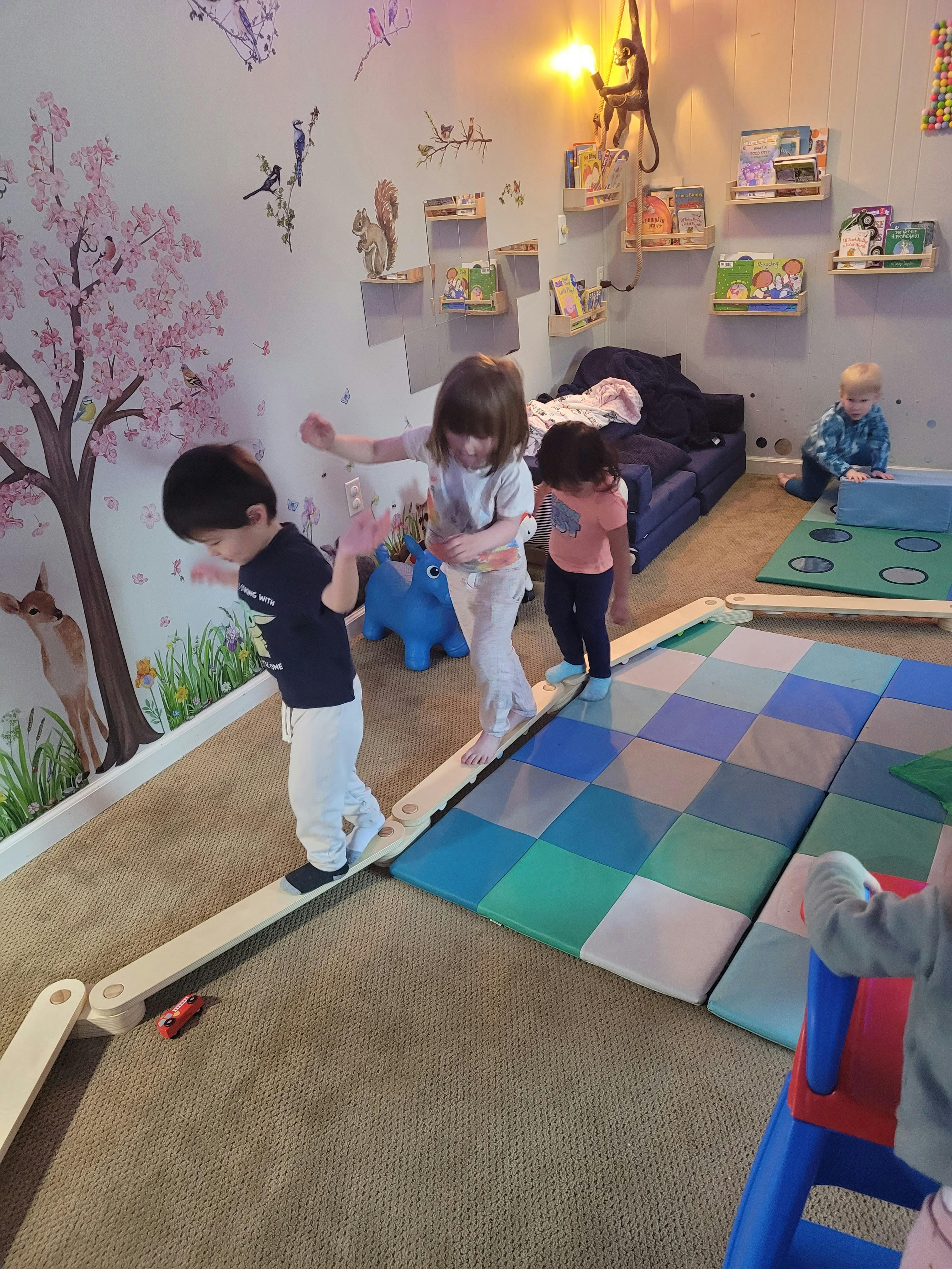 Children playing on a balance beam and floor mats in a room