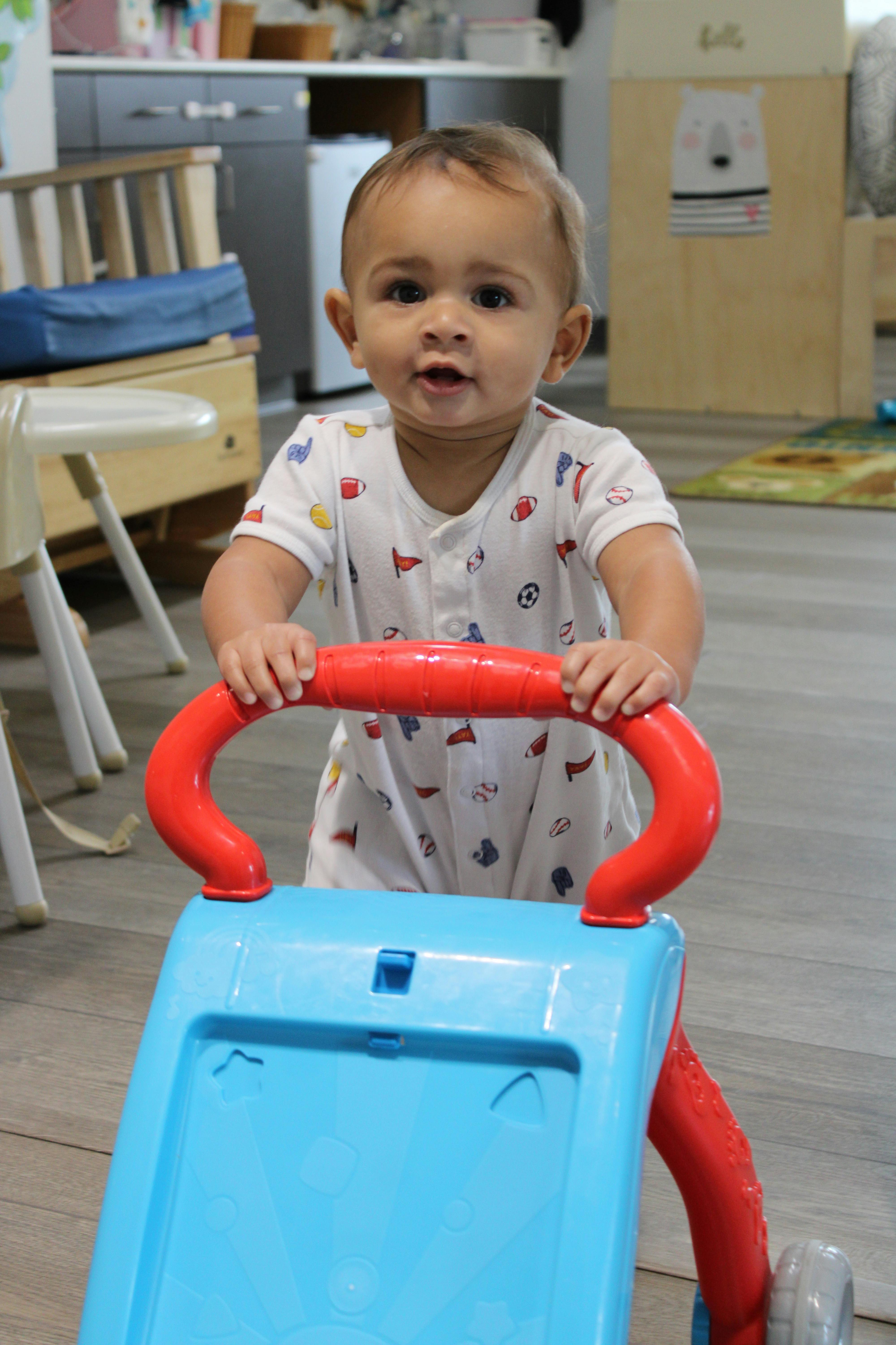 Child standing and holding onto a blue and red toy walker