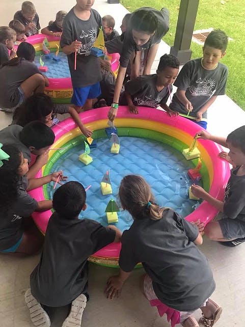 Children playing with toy boats in an inflatable pool