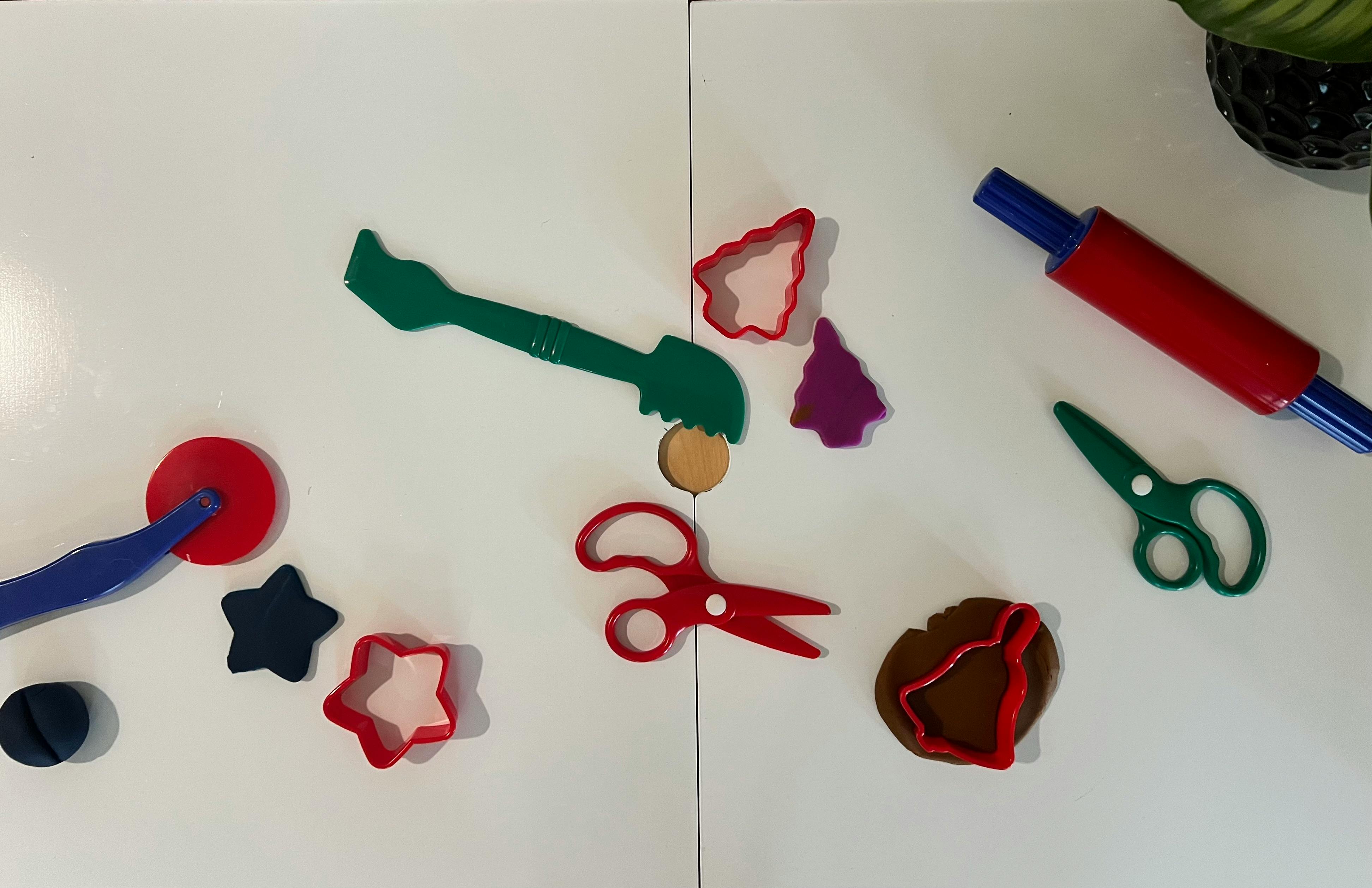 Play-Doh tools and cookie cutters on a white surface