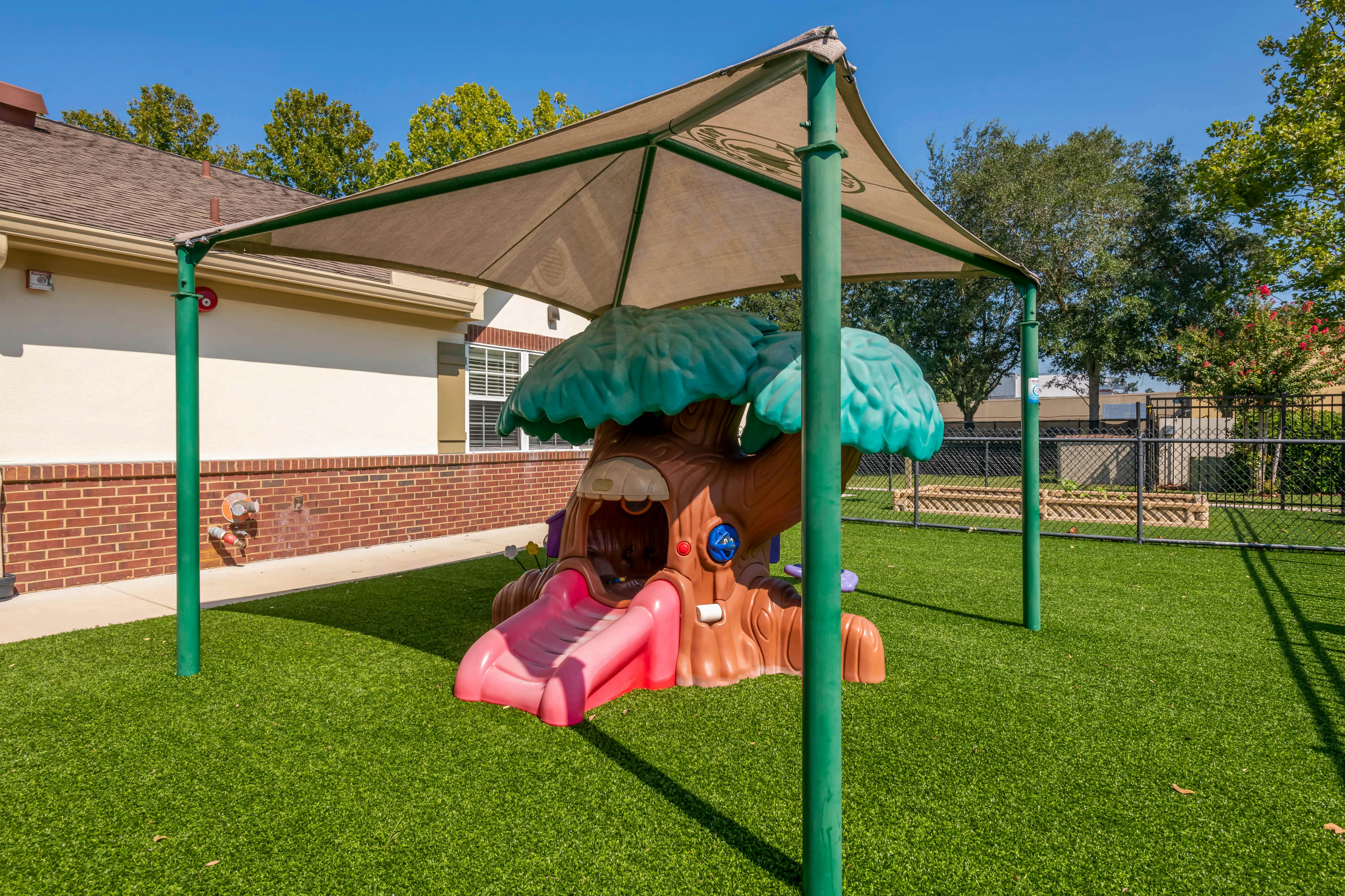 Playground with a tree-shaped slide under a shade structure