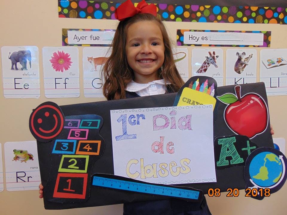 Child holding a sign that says "1er Dia de Clases"