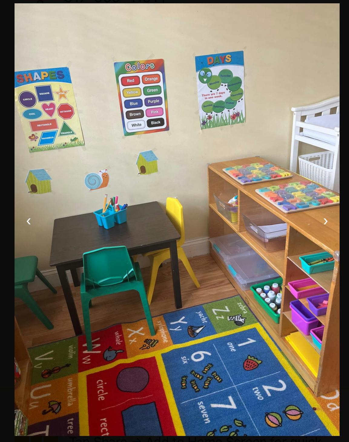 Classroom with a table, chairs, shelves, and educational posters on the wall