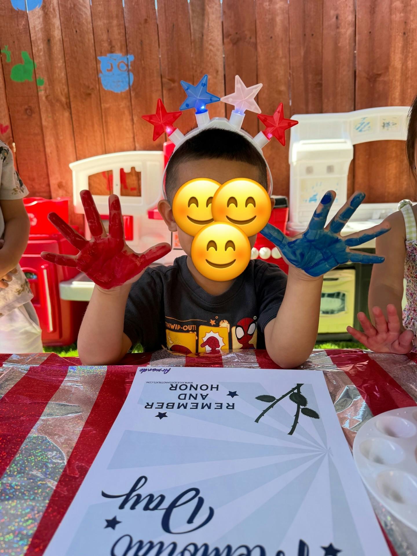 Child wearing star headband with hands covered in red and blue paint