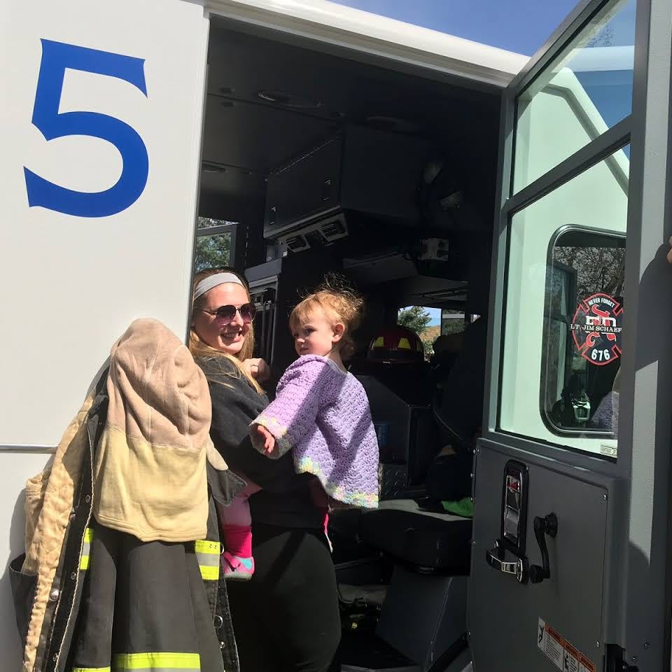 Person holding a child next to a vehicle with a large number 5