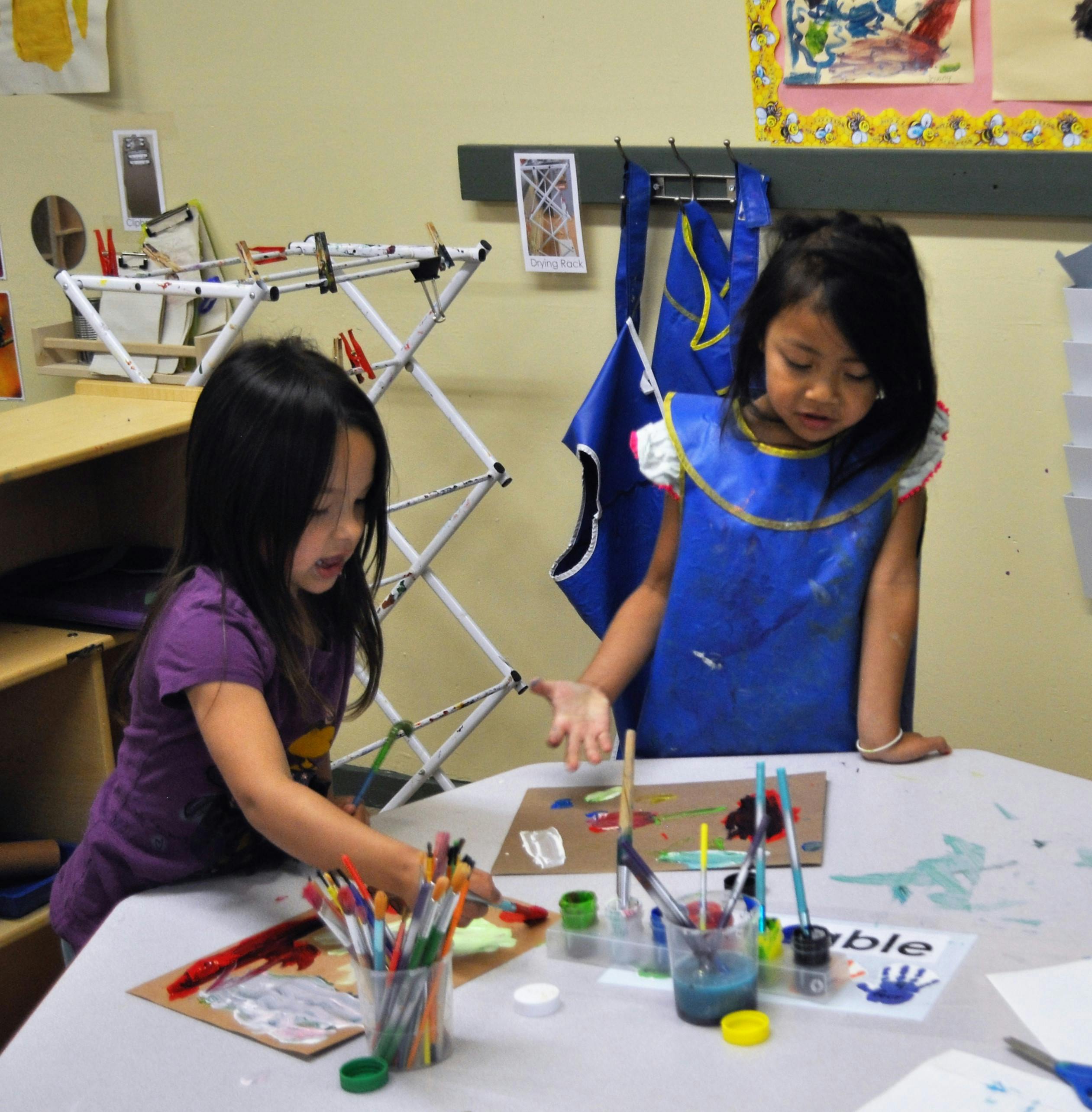 Two children painting at a table in a classroom