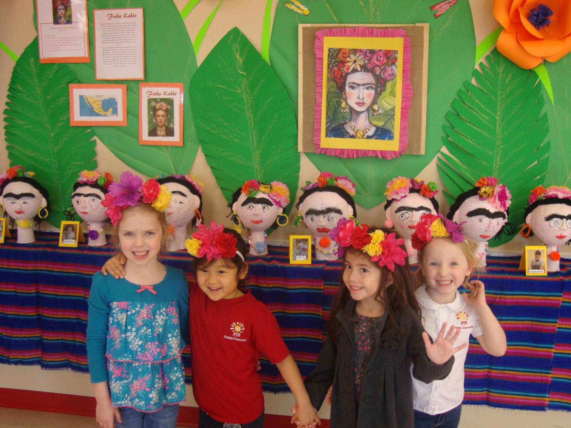 Four children wearing flower headbands standing in front of decorated heads