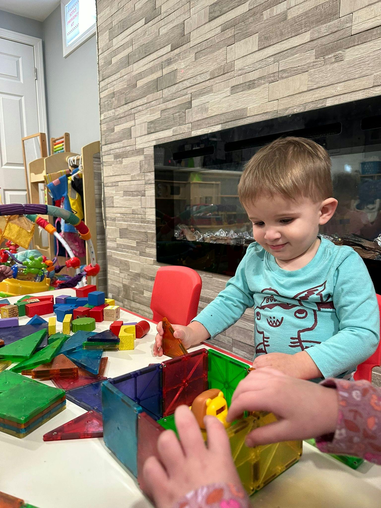 Child playing with colorful magnetic blocks and other toys on a table