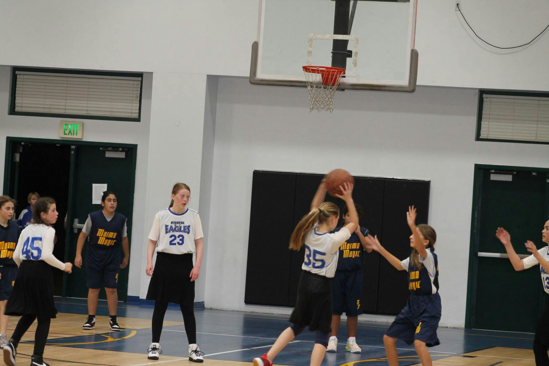 Basketball players on a court, one holding the ball up near the hoop
