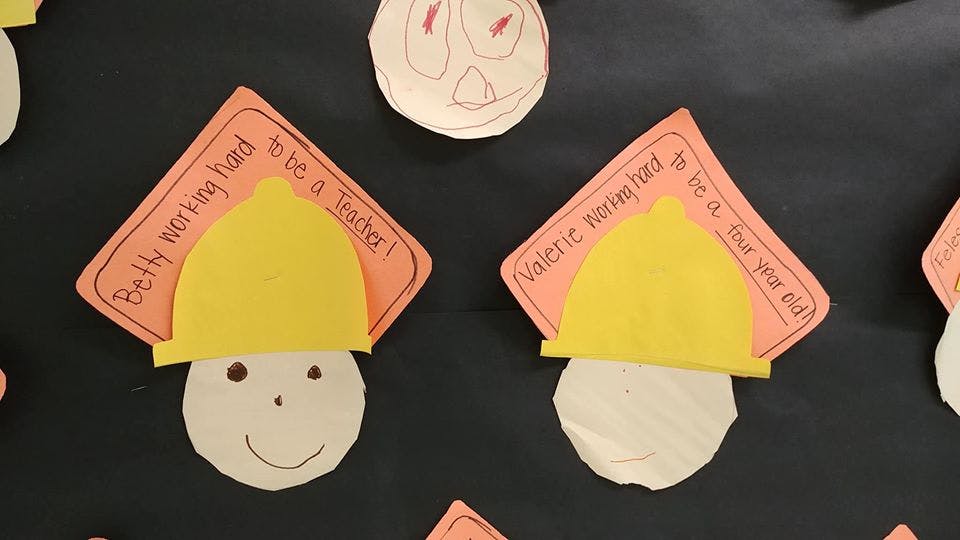 Paper craft faces with yellow hard hats and orange signs