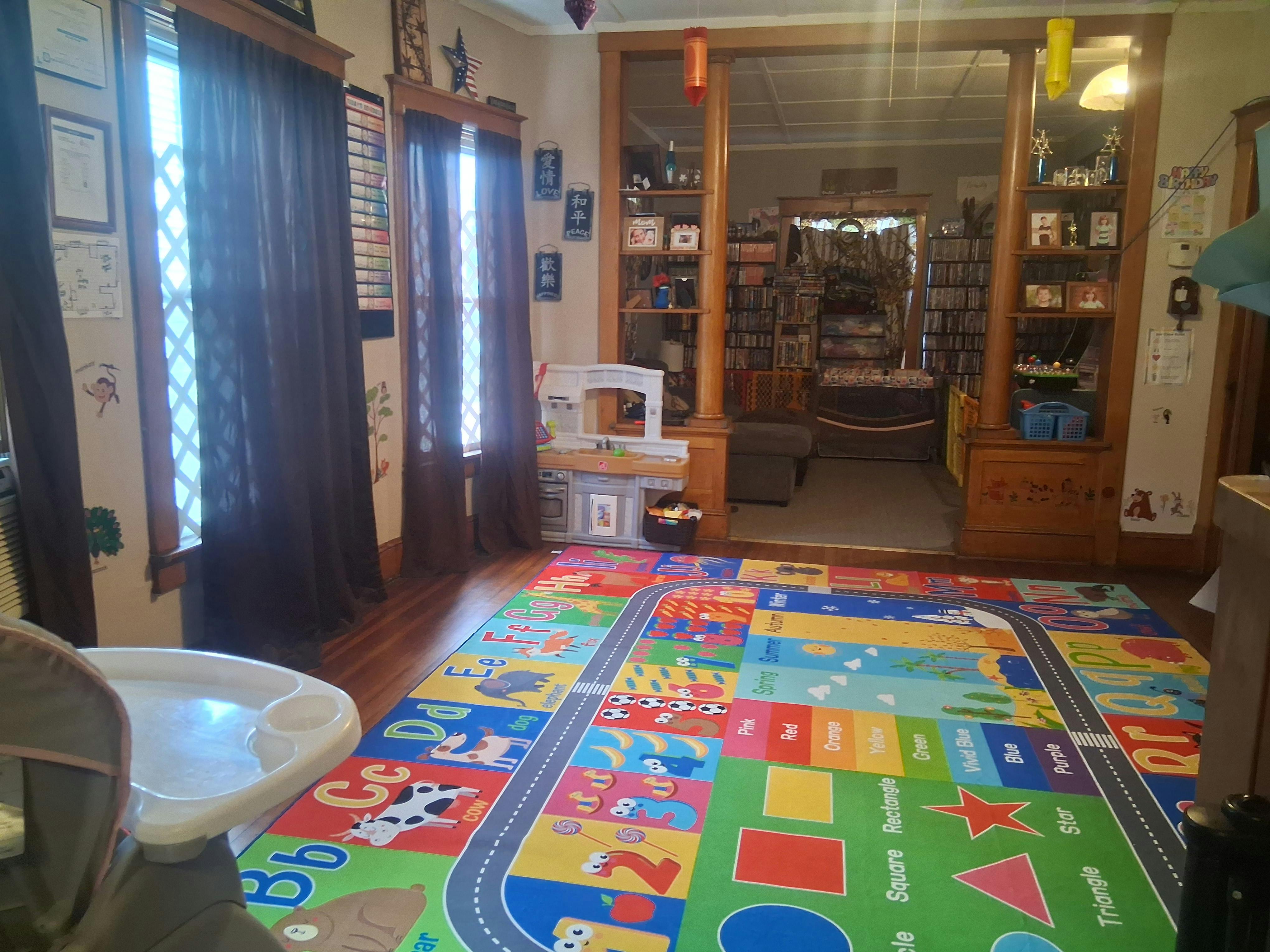 Colorful playmat on a wooden floor in a room with windows and a doorway