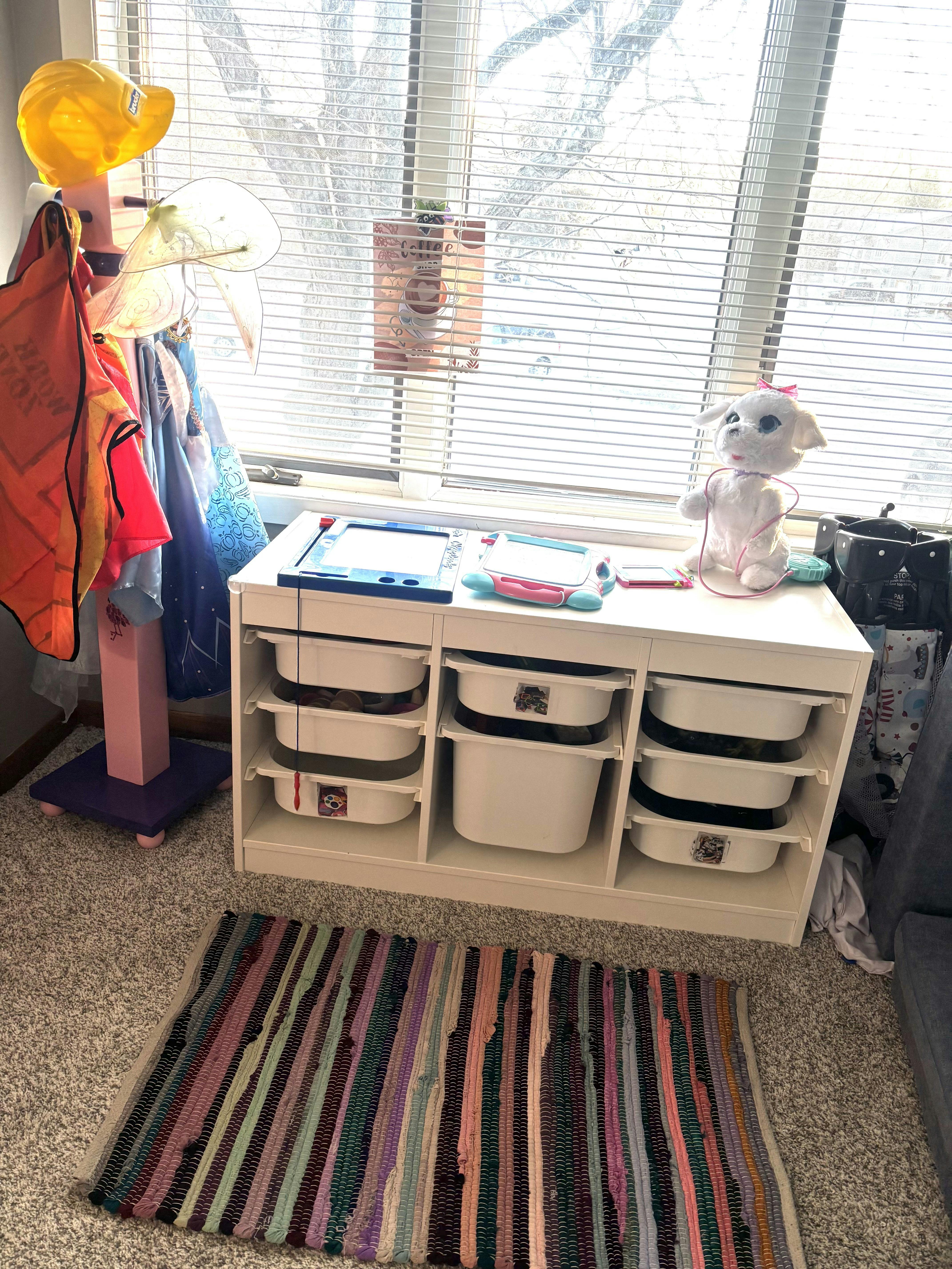 Children's play area with dress-up clothes, drawing boards, and toy storage