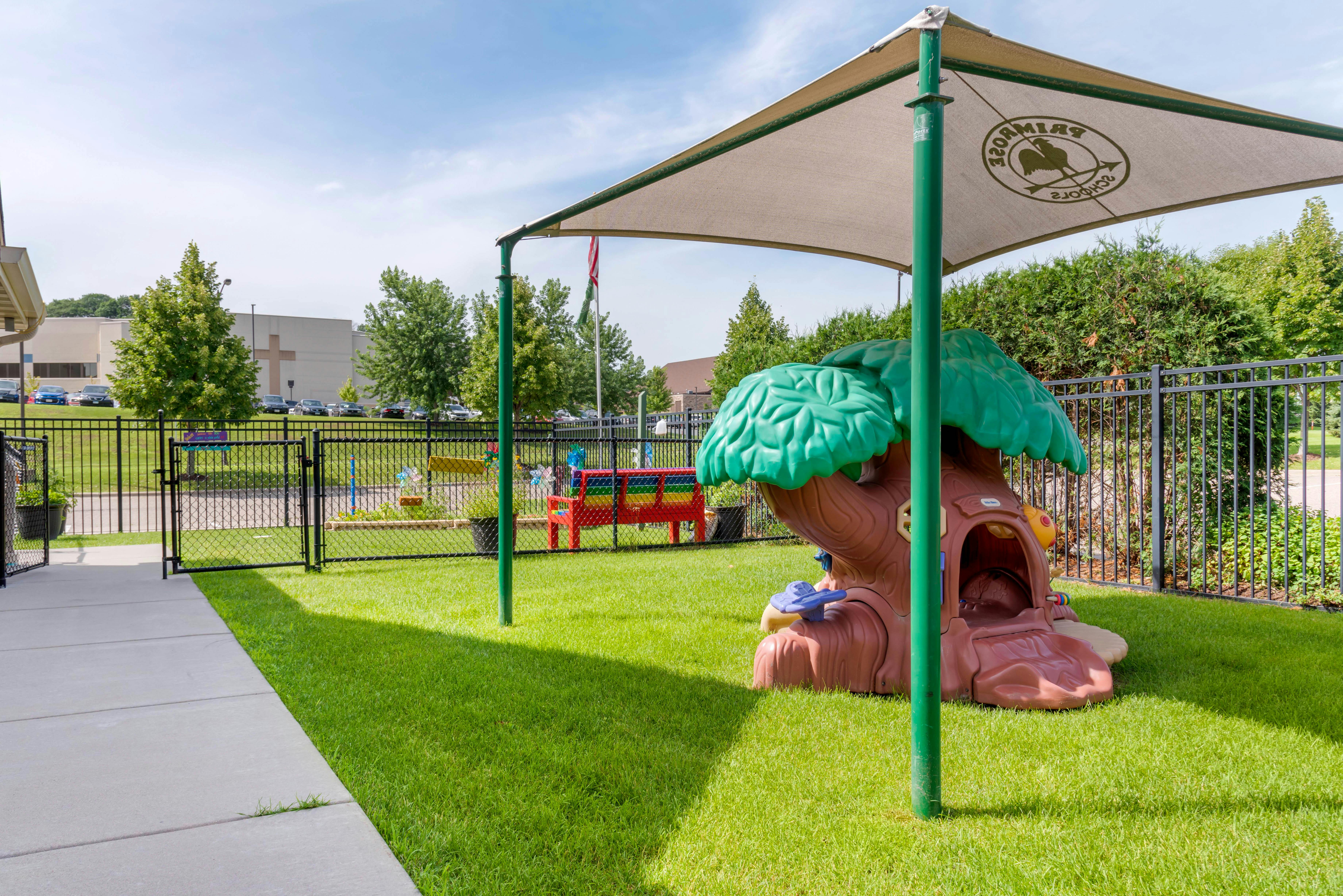 Outdoor playground area with a brown tree-shaped play structure and a red bench
