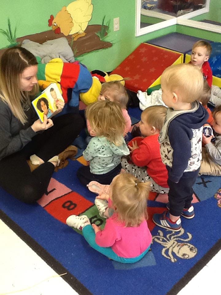 Person reading a book to a group of children in a classroom