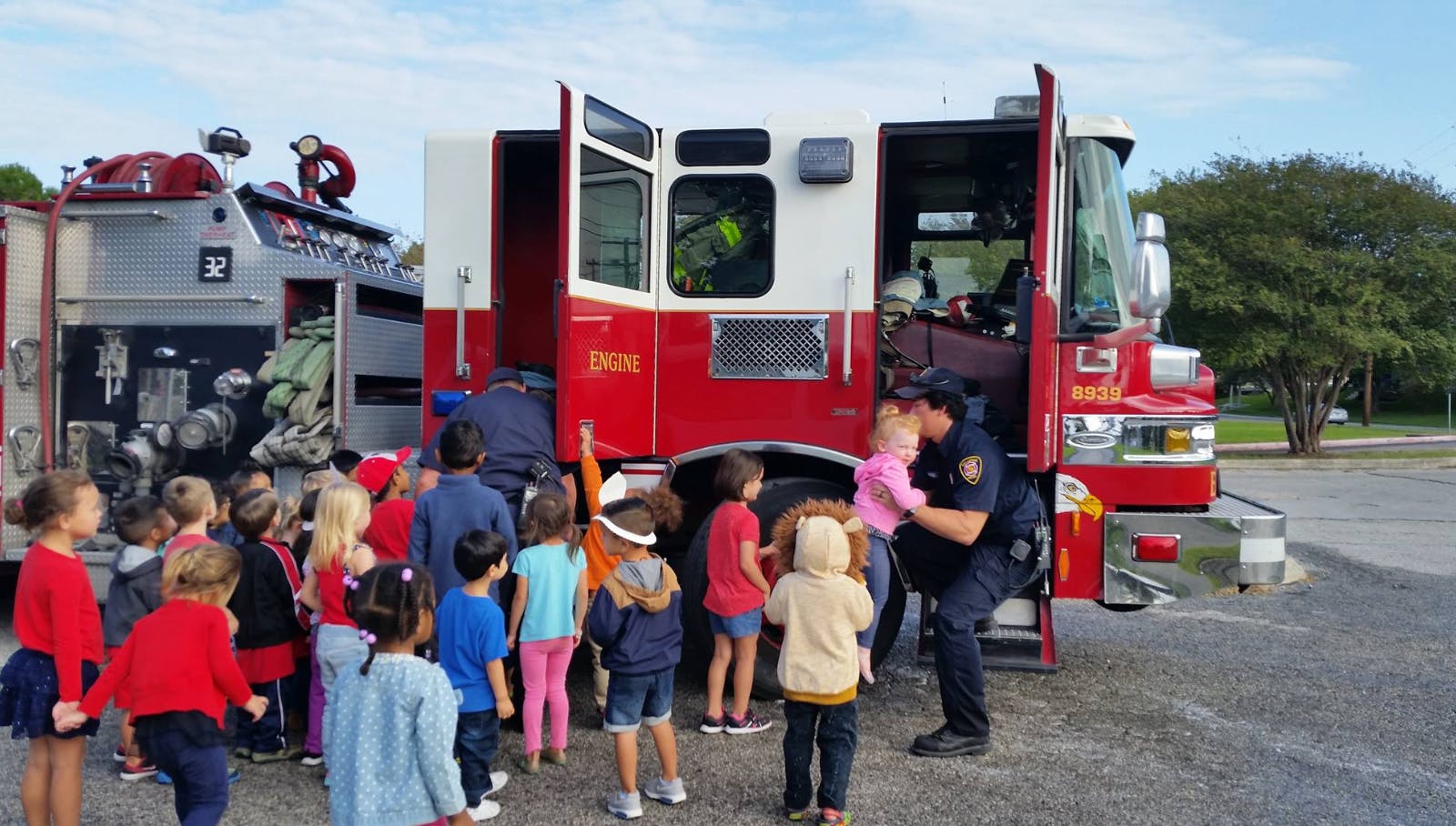 Children gathered around a fire truck with a person in uniform