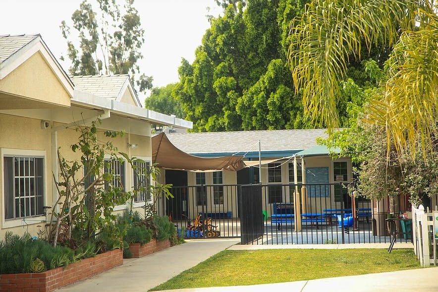 Exterior of a building with a fenced-in play area and green lawn