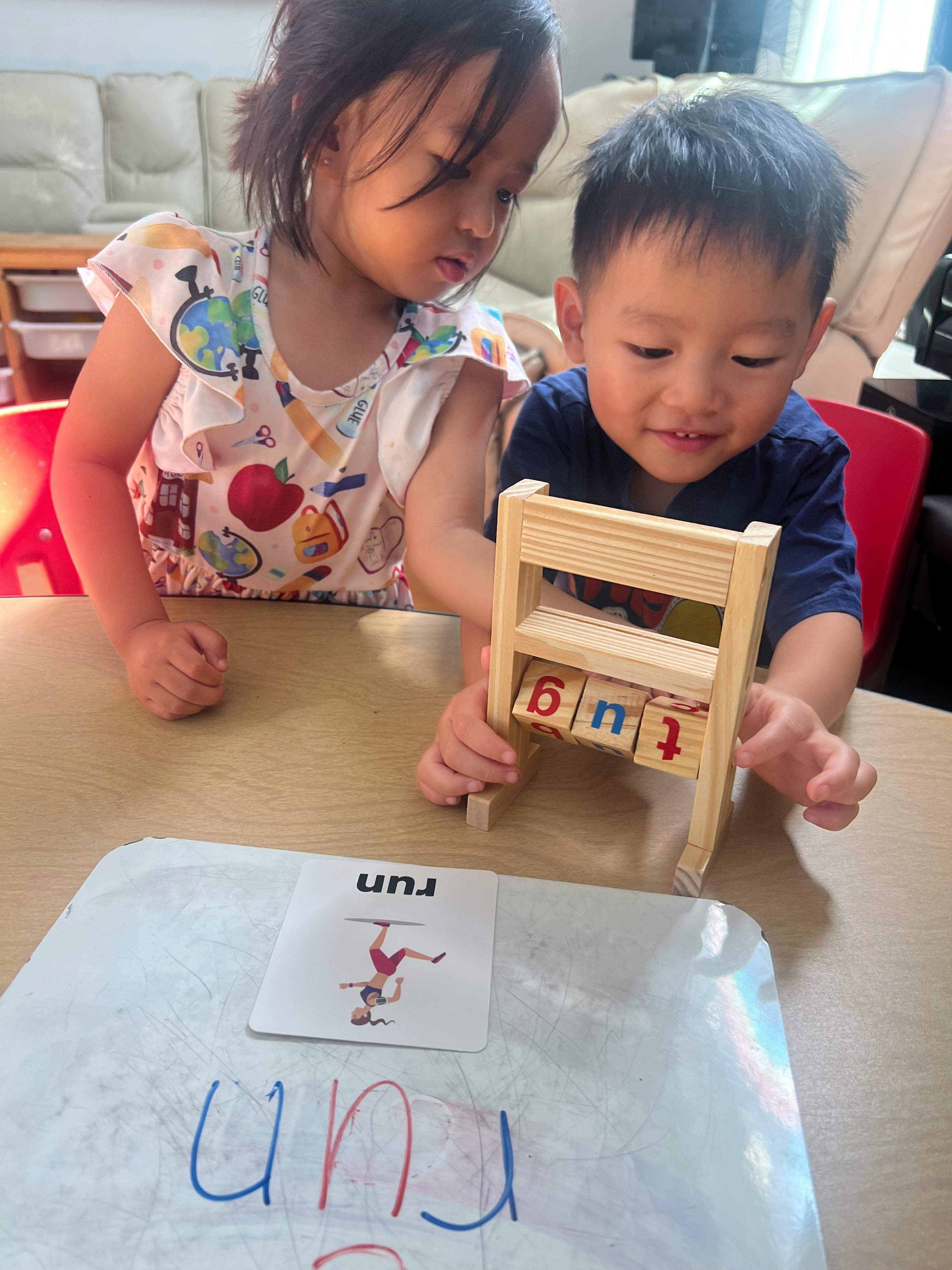 Two children playing with a wooden letter block toy