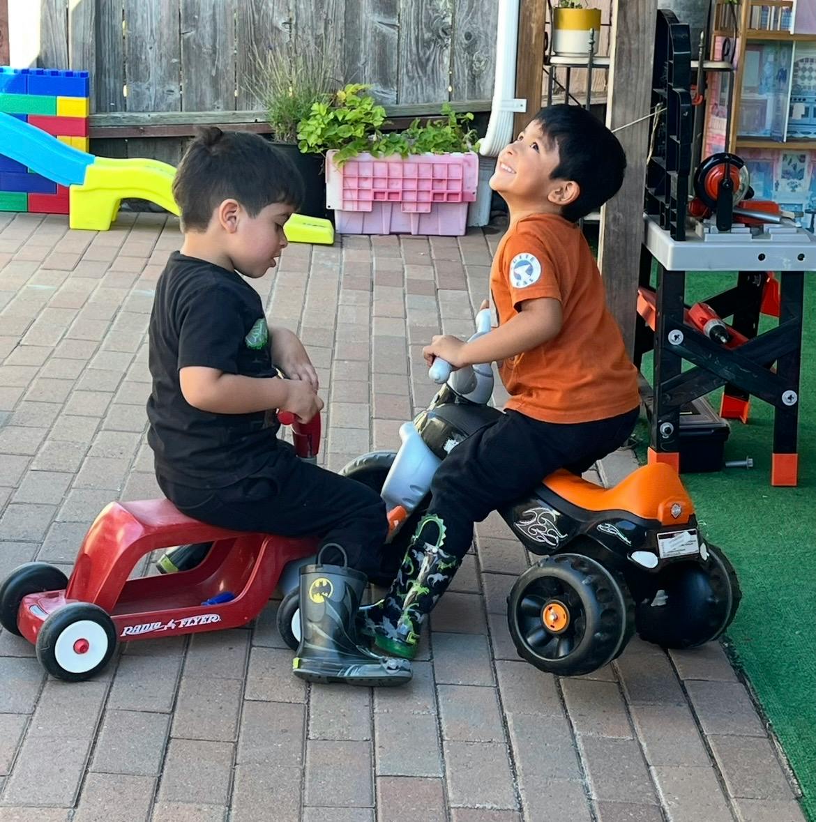 Two children riding on toy vehicles outdoors