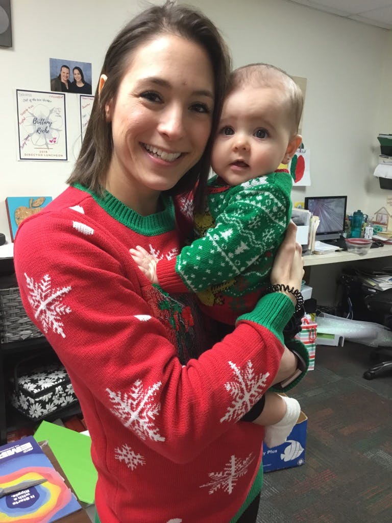 Person in red sweater holding a child in a green sweater