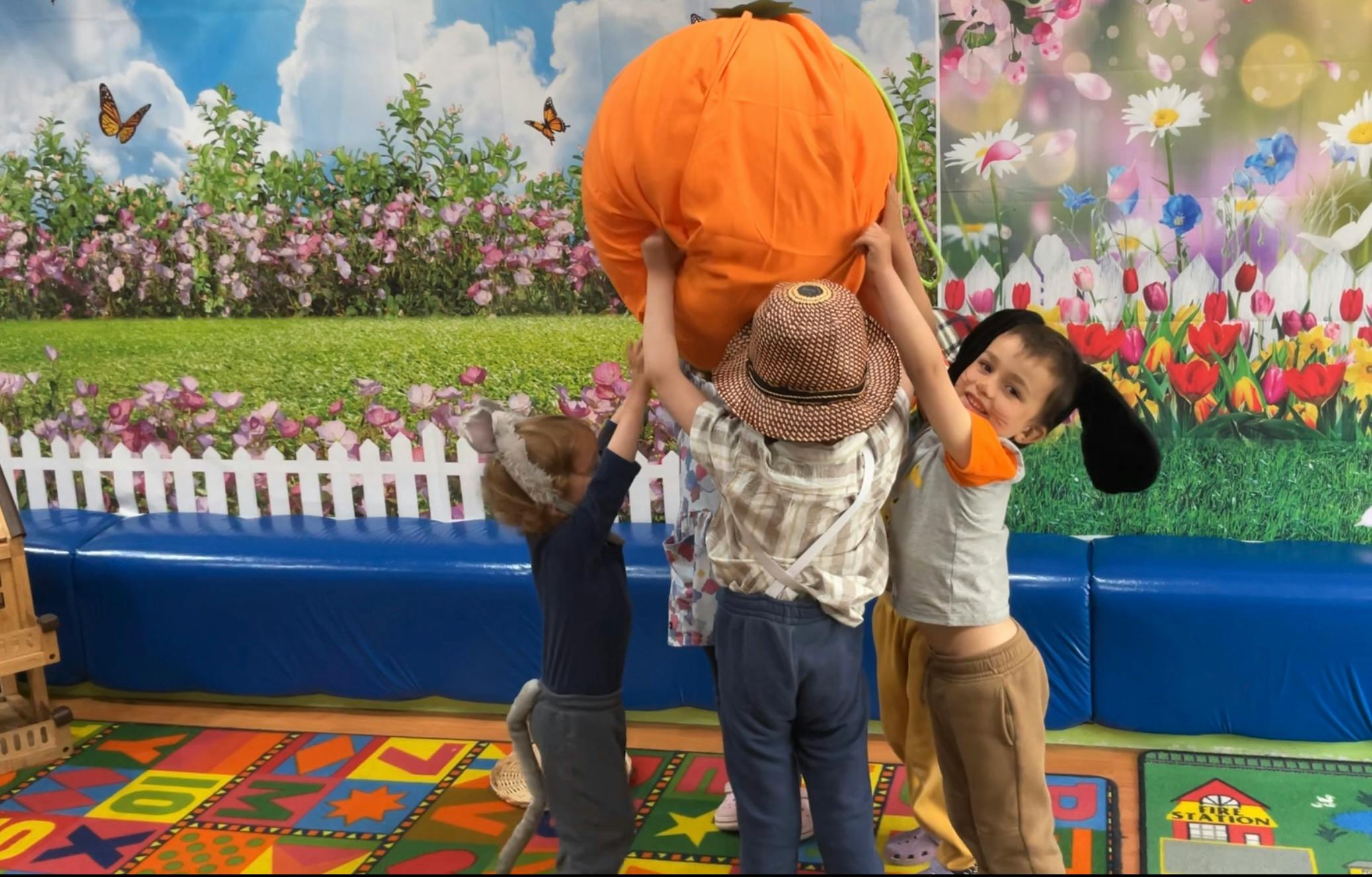 Three children holding up a large orange object
