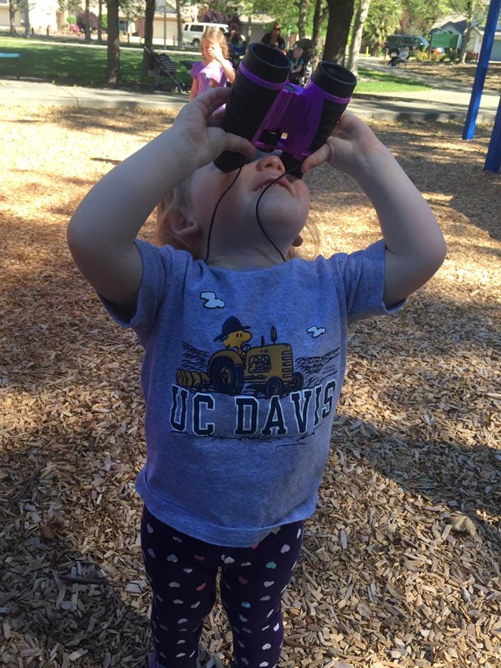 Child looking up through purple binoculars