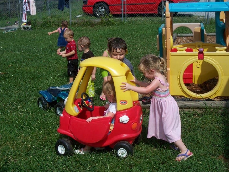 Children playing with a toy car outdoors