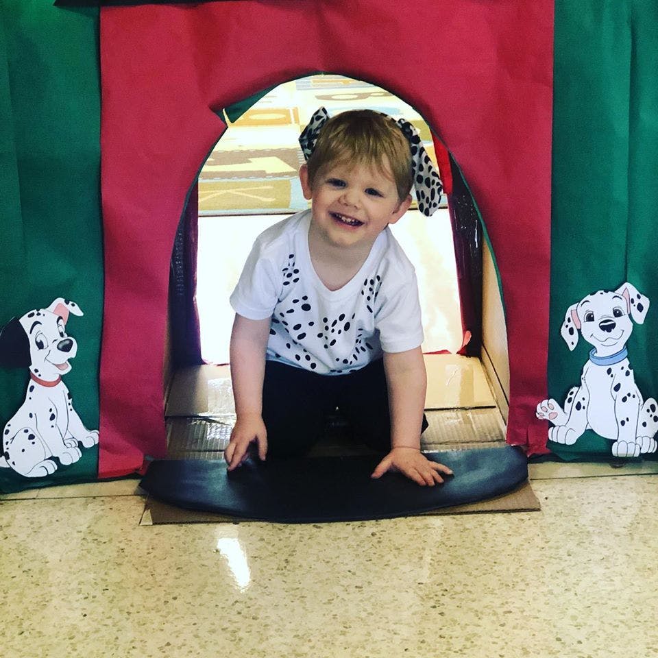 Child in a spotted shirt crawling out of a play tent
