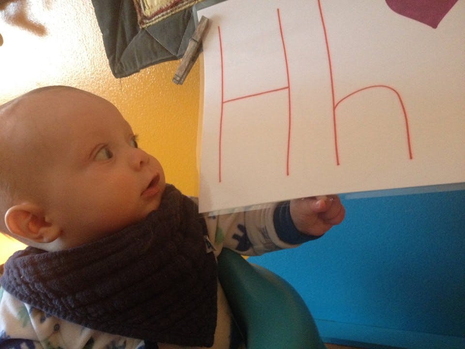 Child looking at a paper with the letter H drawn on it