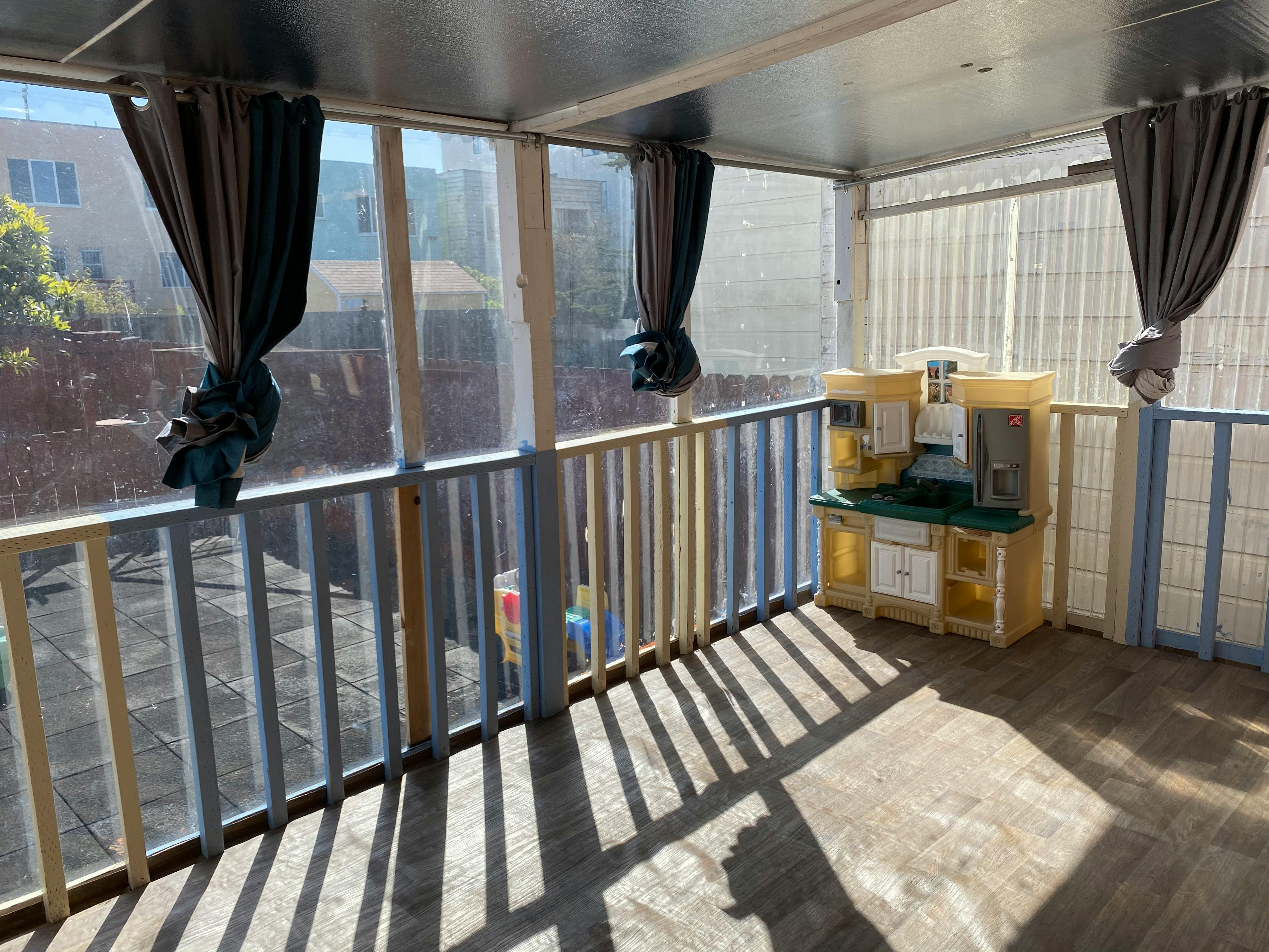 Screened-in porch with a toy kitchen set and curtains