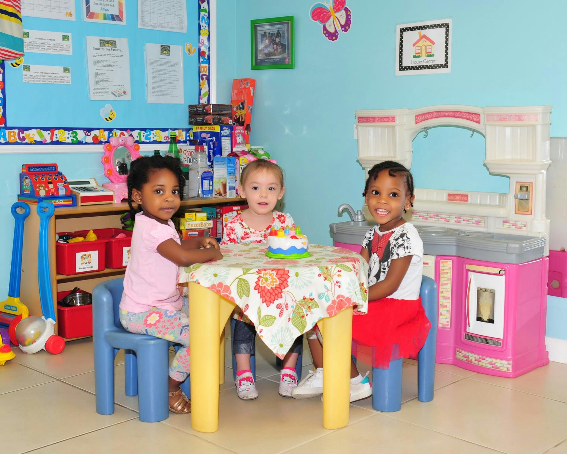 Three children sitting at a small table in a classroom