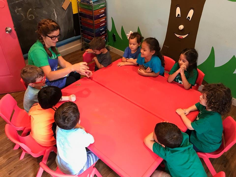 Adult and children sitting around a red table in a classroom