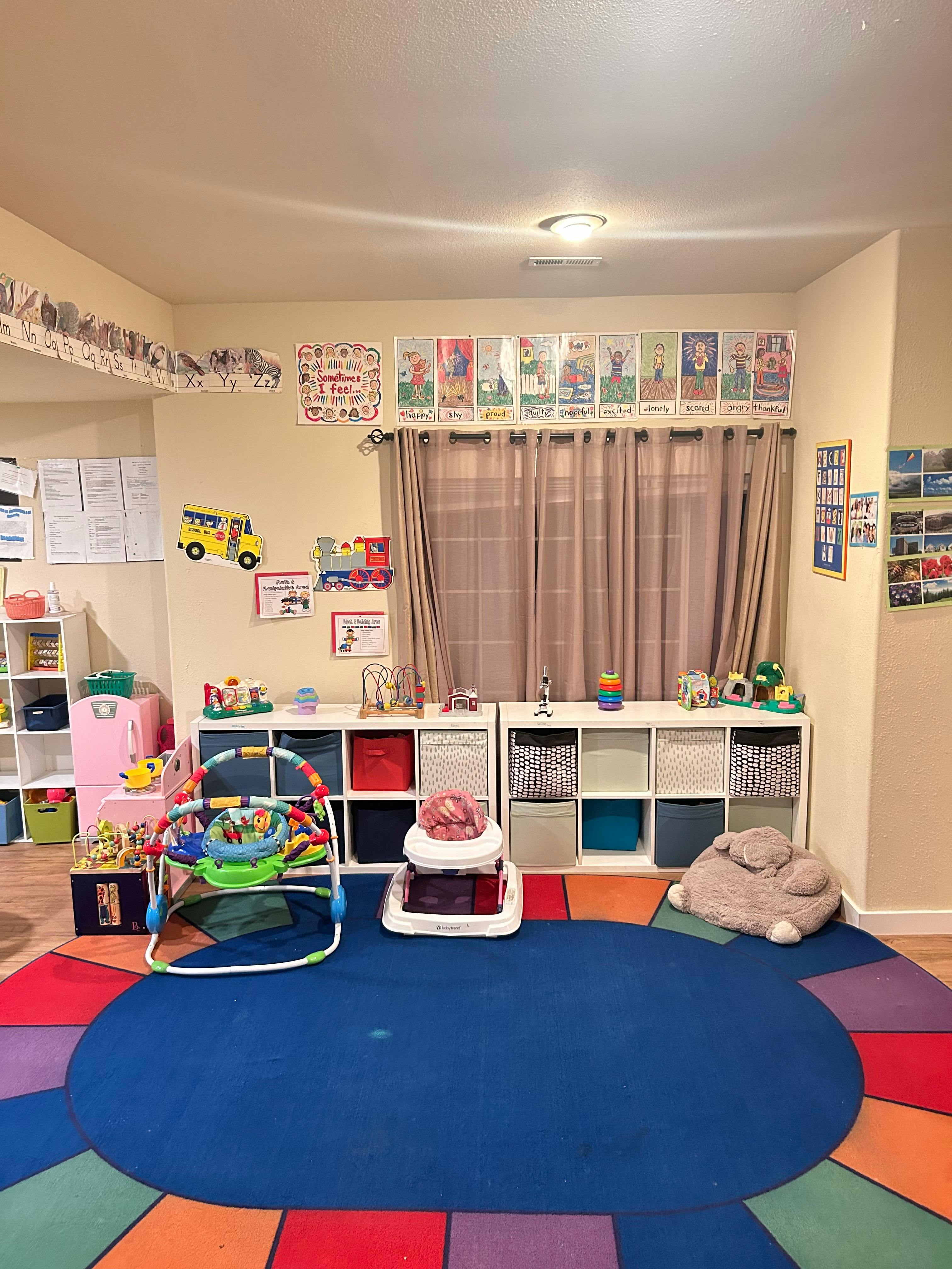 Playroom with colorful rug, baby activity center, and storage shelves