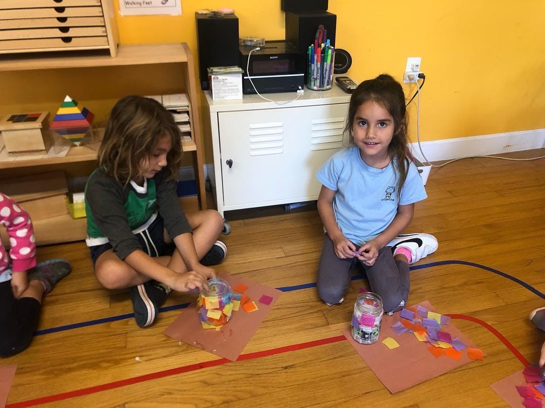Two children sitting on the floor making crafts