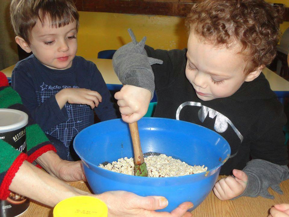 Two children mixing ingredients in a blue bowl
