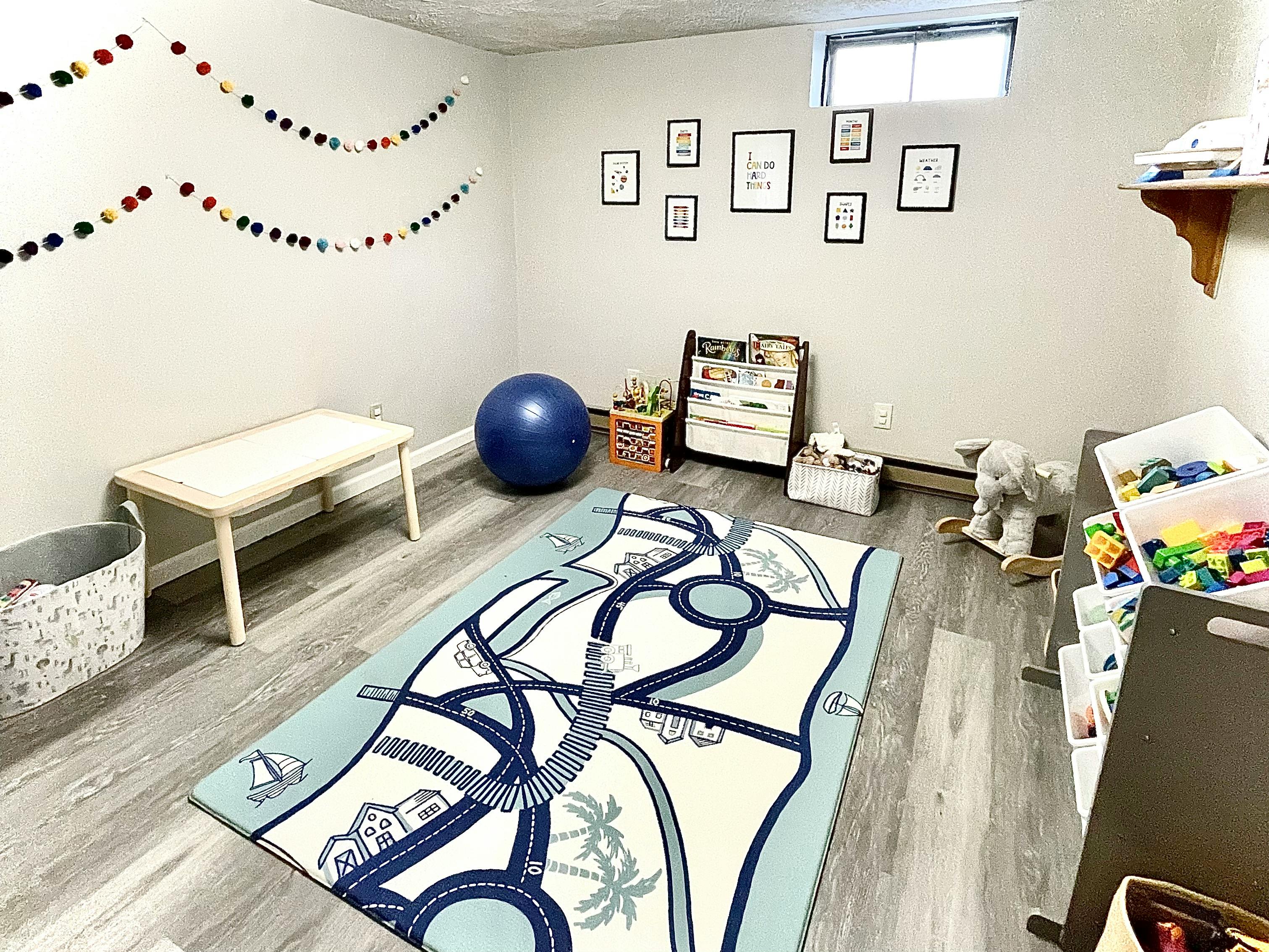Playroom with a road map rug, blue exercise ball, and small table