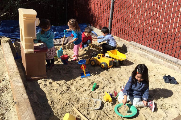 Children playing in a sandbox with toys