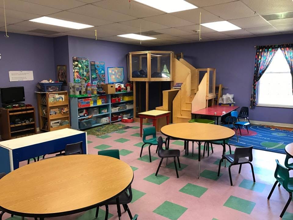 Playroom with tables, chairs, shelves, and a wooden play structure