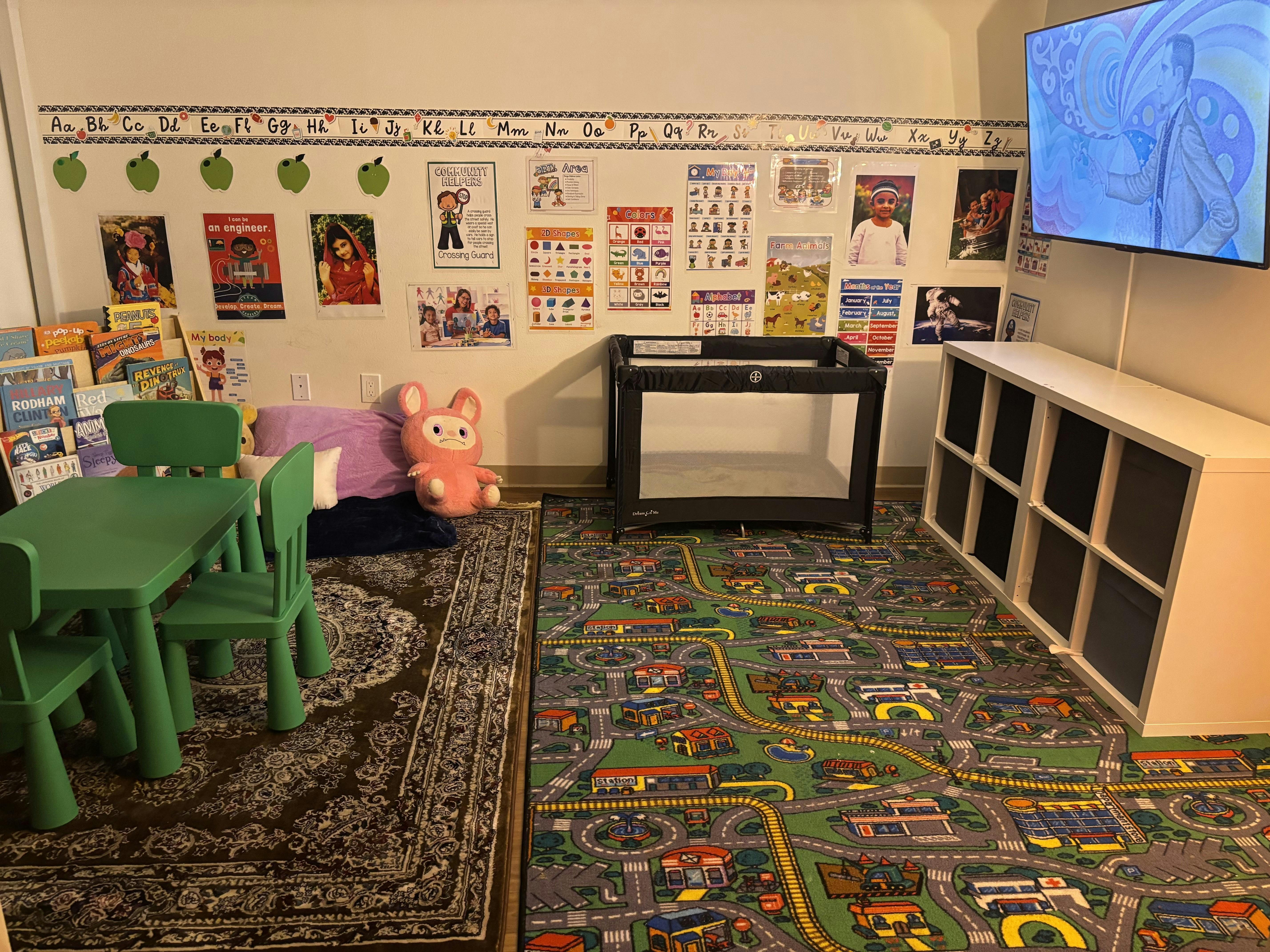 Playroom with small green table and chairs, playpen, and road map rug