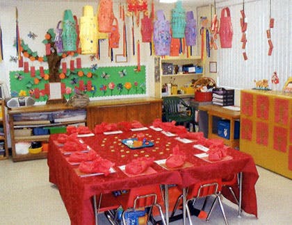 Classroom decorated with colorful lanterns and a large red table set for a meal