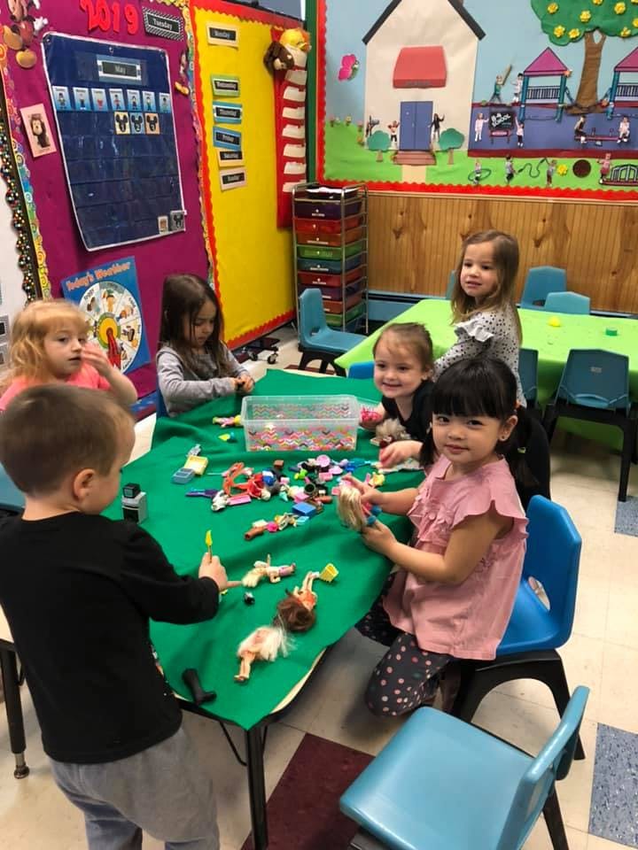 Children playing with toys at a table in a classroom